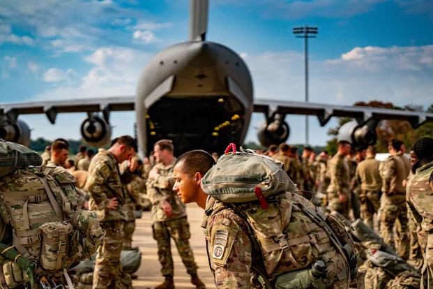 Paratroopers buddy rig their parachutes.